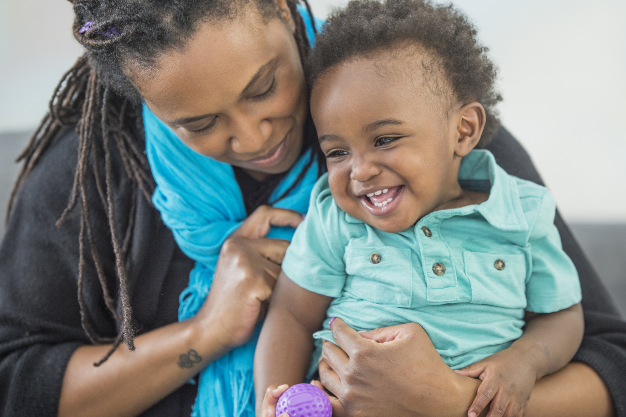 A mother is holding her toddler and they are playing together on mother's day.