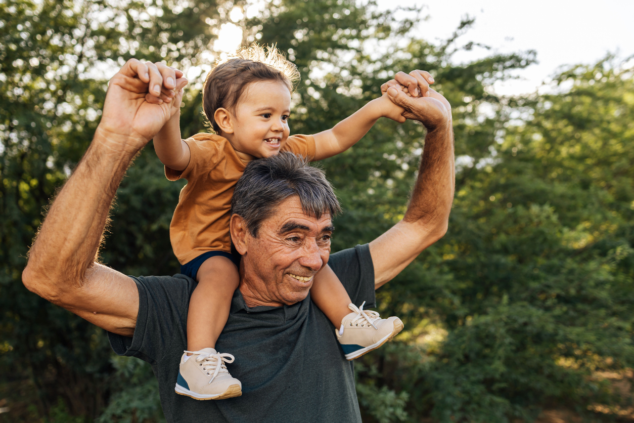 Playful grandfather spending time with his grandson in park on sunny day