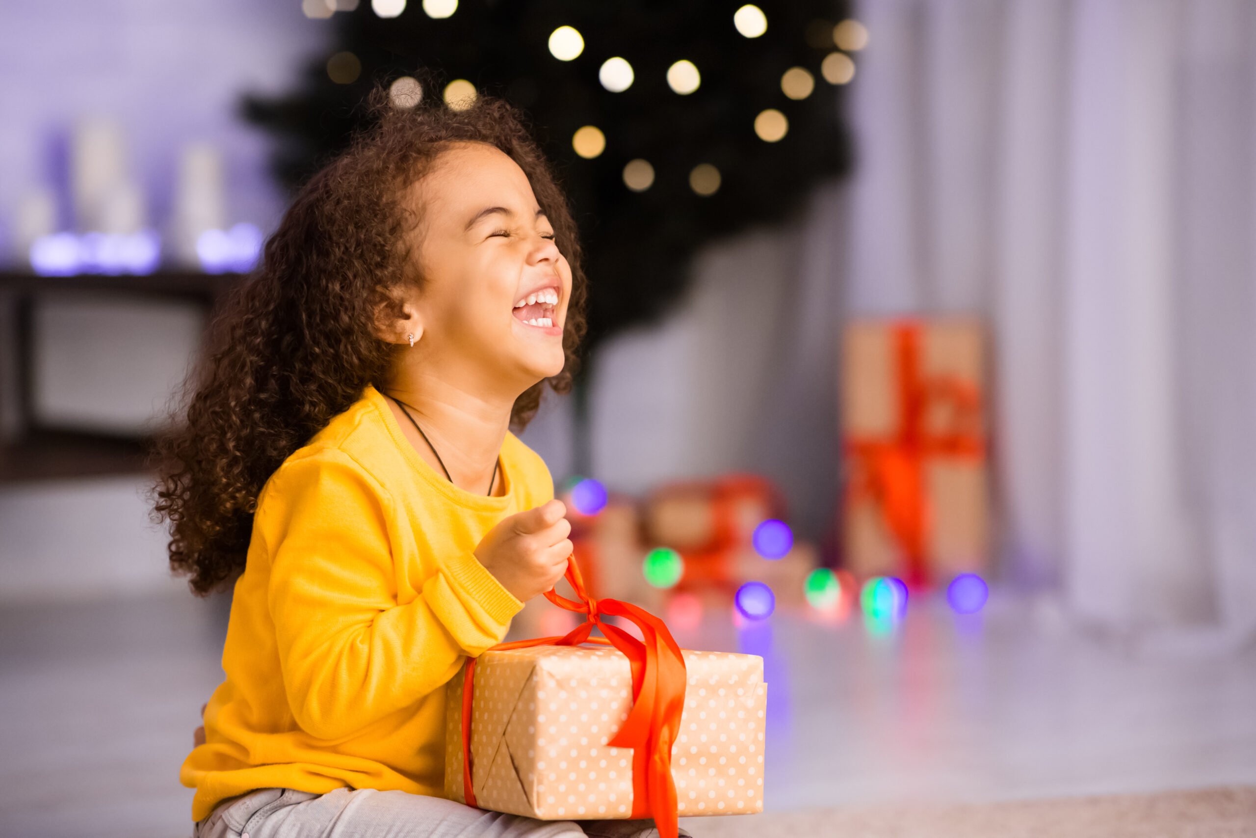 Excited african girl laughing with Christmas gift, empty space
