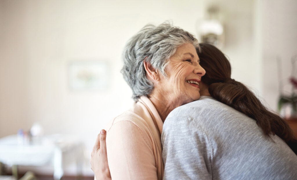Shot of a senior woman hugging a young nurse in a retirement home
