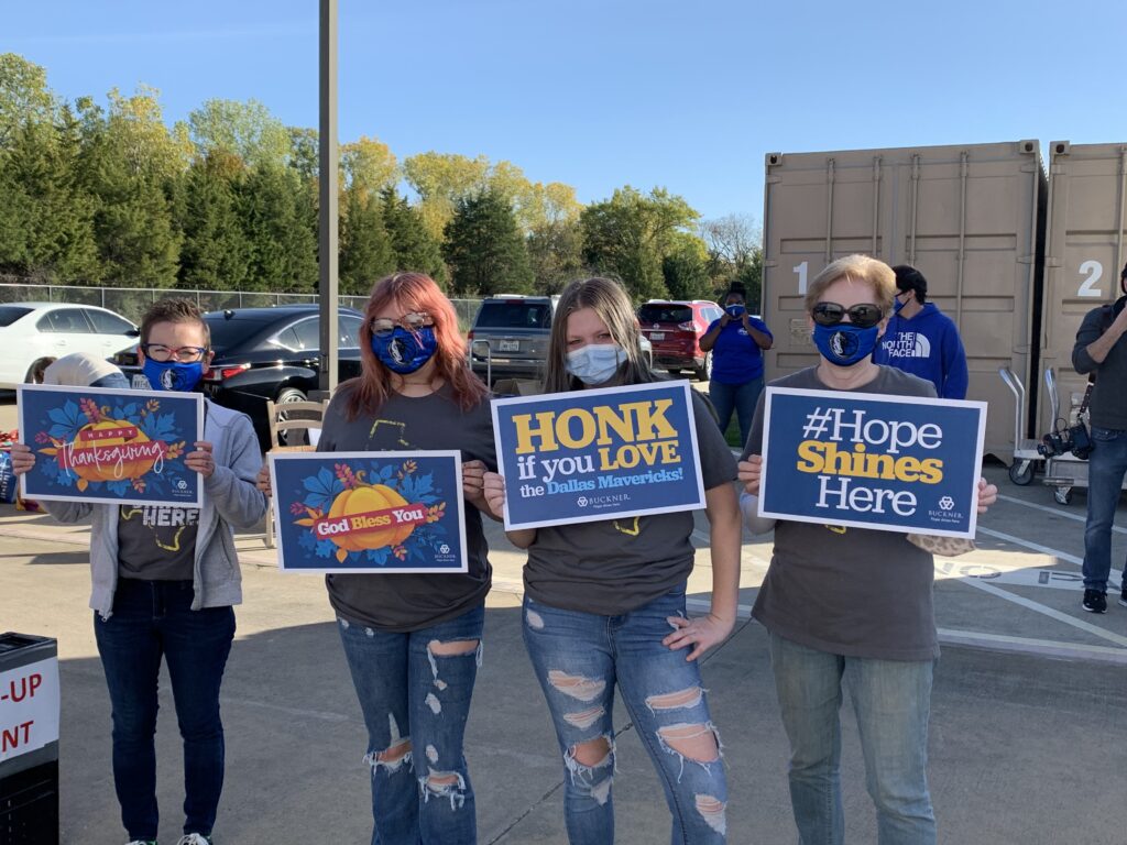 volunteers-hold-signs-during-the-mavericks-turkey-giveaway